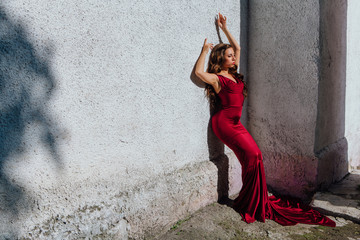 Beautiful young woman in a long red evening gown with a train