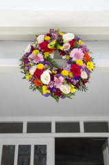 Fresh wreath of roses and gerberas on wall