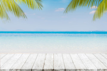 Empty wood table top and blurred Palm tree summer beach with blue sea and sky background. - can used for display or montage your products.