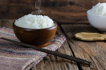cooked rice in wooden bowl with smoke on wooden floor