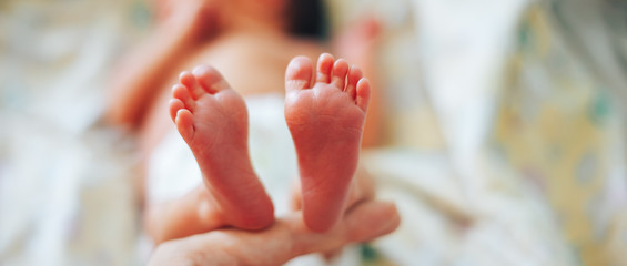 feet of newborn baby in mother's hand