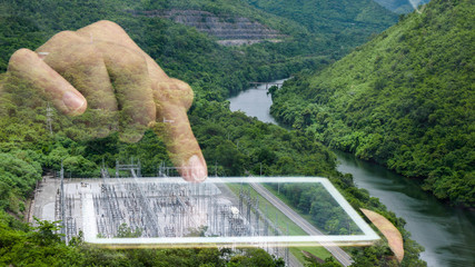 Double exposure of hand using tablet with hydroelectric power plant