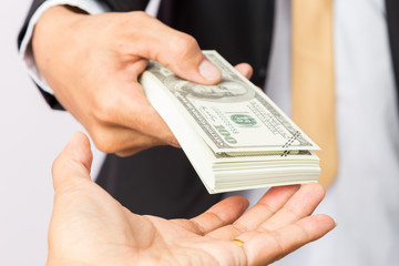 businessman in suit gives dollors US to a man