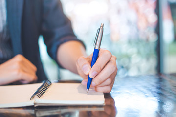 Business woman writing on a notebook.with a pen in the office