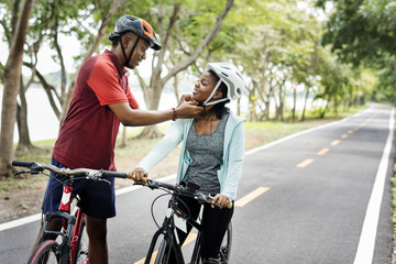 Man fastening the bike helmet for his girlfriend