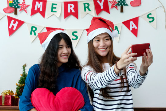 Two asian women selfie smart phone in Christmas party celebration, LGBT couple, friends Christmas party
