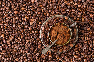 Overhead view of a bowl of ground coffee on a roasted whole
