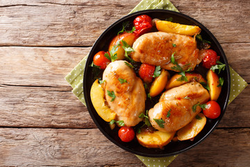 Sour sweet chicken breast baked with peaches, tomatoes, onion, parsley and honey garlic sauce close-up. horizontal top view
