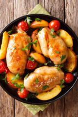 baked chicken breast with peaches, tomatoes, onions closeup on a plate. Vertical top view