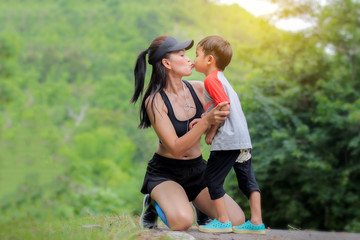 Fototapeta premium Young mother wear sport cloth kiss her son boy at nature outdoors.Concept image healthy family.