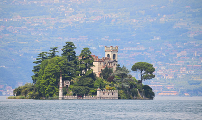 Isola di Loreto, tiny island inside Iseo Lake, Lombardy, Italy, old castle surrounded by trees with...