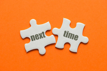 Two white details of puzzle with text Next Level on orange background, close up.