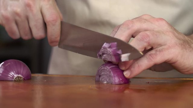 Tracking shot of chef dicing red onion