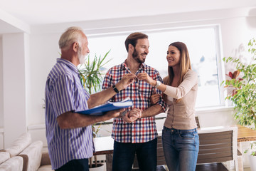 Real estate agent giving keys to couple of customers