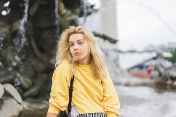 selective focus of young attractive woman looking at camera in front of fountain