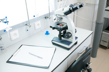 Shiny microscope on table in empty science laboratory, copy space