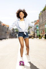 Best hobby. Charming young woman riding her purple mini skateboard and smiling cheerfully, enjoying the ride