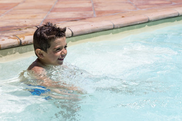 Cute little boy playing in the swimming pool at summer