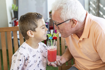 Grandfather and grandson drinking watermelon juice at the same time