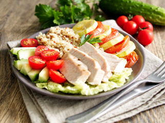 Healthy vegetable buddha bowl lunch with turkey, vegetables and quinoa on brown wooden background. Side view.