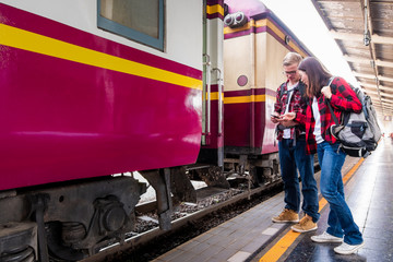 Happy young couple travellers together on vacation at the train station, travel concept, couple concept