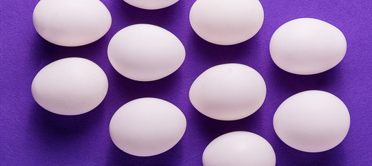 Organic white eggs on purple  backgound.
