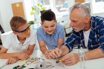 Modern electronics. Happy curious children listening to their grandfather while learning new skills