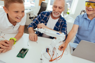 New device. Selective focus of a robot standing on the table with positive cheerful kids looking at it