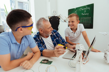 Interactive classroom. Happy positive boy talking to his friend while having a science class