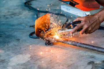Industrial worker using welder machine is welding a spade tool