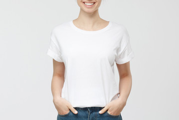 Young european woman standing with hands in pockets, wearing blank white tshirt with copy space for...