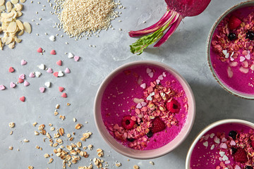 Berry beetroot fresh smoothies for breakfast in ceramic bowls on a gray stone background with...