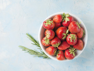 Ripe strawberry in bowl with rosemary top view