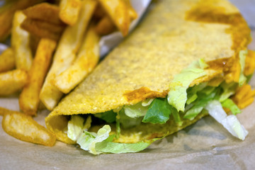 A picture of a taco with pork meat and french fries 