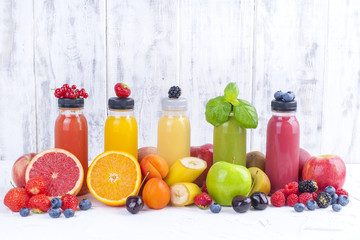 Many different fruits and berries and juices in plastic bottles. Watermelon, banana, applcsin, blueberries, strawberries, basil on a white background. Vitamin and healthy food. Detox. Copy space.