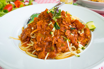 Italian linguine with vegan bolognese sauce based on soy beans and vegetables served on a white plate