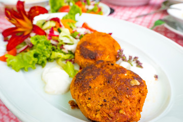 Meatless vegan patties with rolled oats and zucchini served on a white plate with salad and soy yogurt 