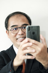 Happy businessman using mobile phone to take selfie 