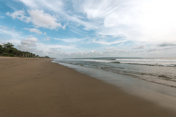 Fototapeta na wymiar sea wave reach sandy beach under cloudy sky