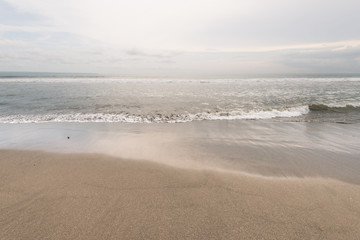 sea wave reach sandy beach under cloudy sky