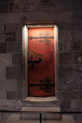 Old red magnificent door with stone walls and a little light