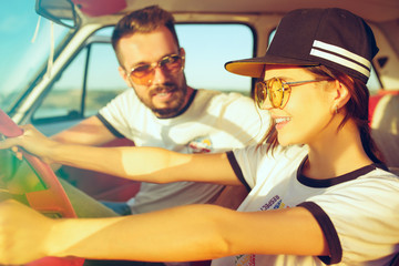 Laughing romantic couple sitting in car while out on a road trip at summer day