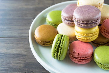 Colorful bright almond macarons or macaroons on wood background
