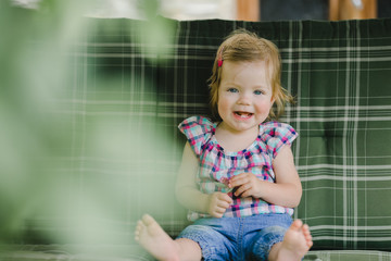 Fototapeta premium The small child sits on the sofa in room