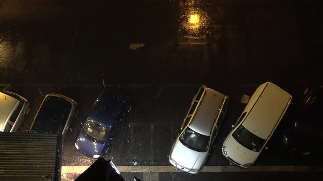 Top down view of city streets at night and heavy rainfall and thunderstorm flashes illuminating the streets and parked cars for short period of time typical city scene during rain season 4k quality