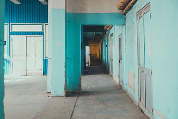 A corridor In a rickety building.  going into the distance, blue weathered walls.