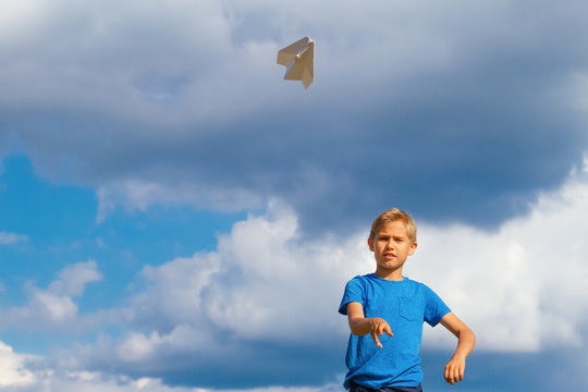 Boy throwing paper plane against blue sky