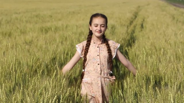 young girl walking in the field with wheat