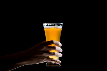 Hand holding glass of craft beer on black background