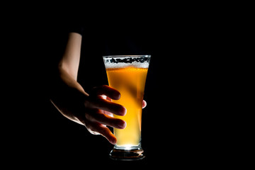Hand holding glass of craft beer on black background